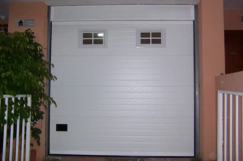 Puerta seccional blanca residencial con ventanillas de claridad superiores